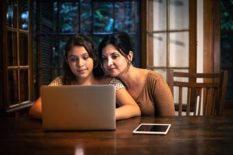 Mother helping her teenager doing homework at home at night