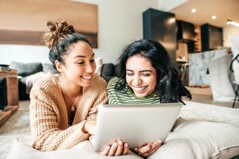 Two female students with digital tablet and cellphone at home