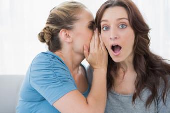 Woman whispering secret to her friend