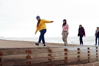 4 girls walking on wall at the beach