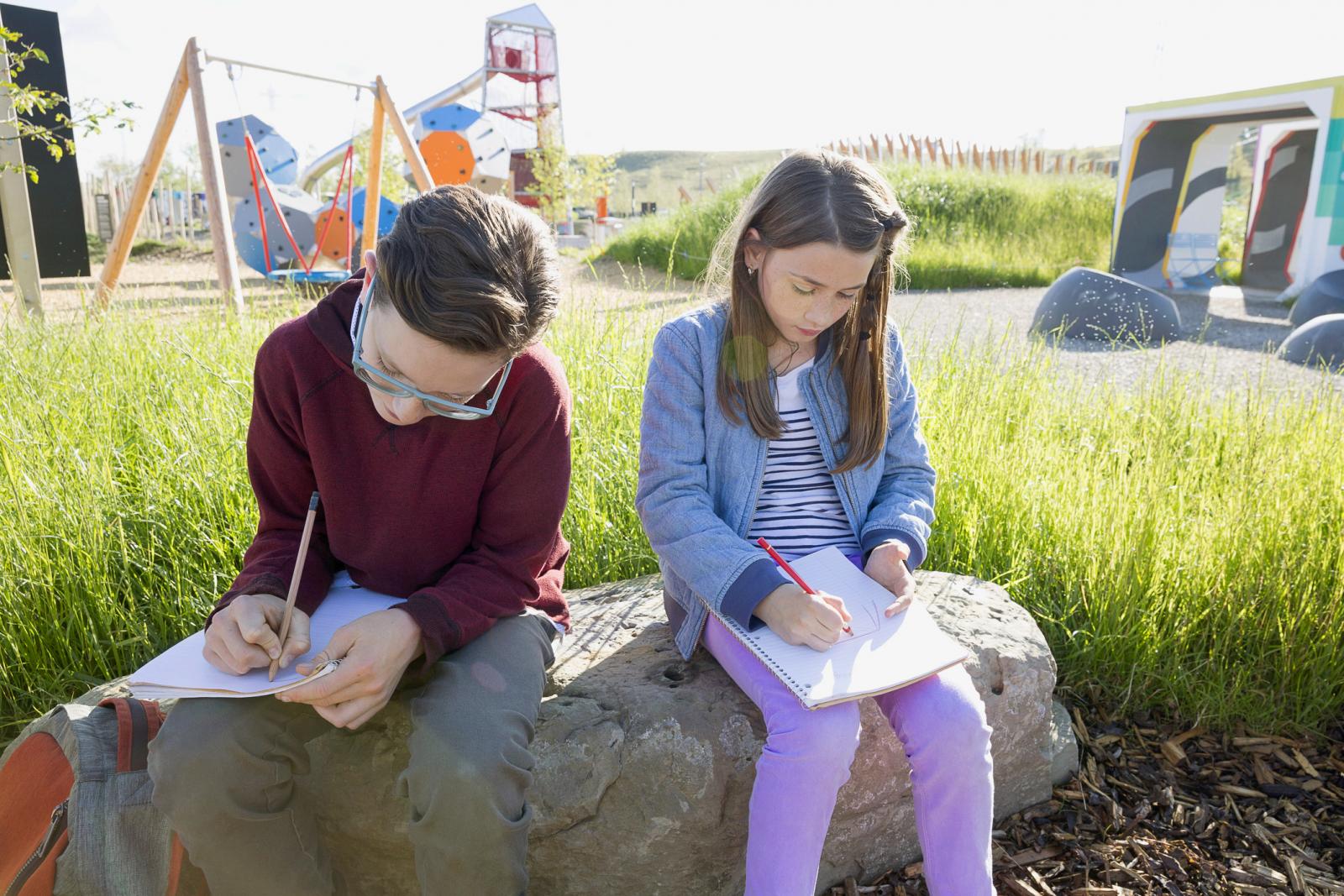 Students doing their homework near sunny playground