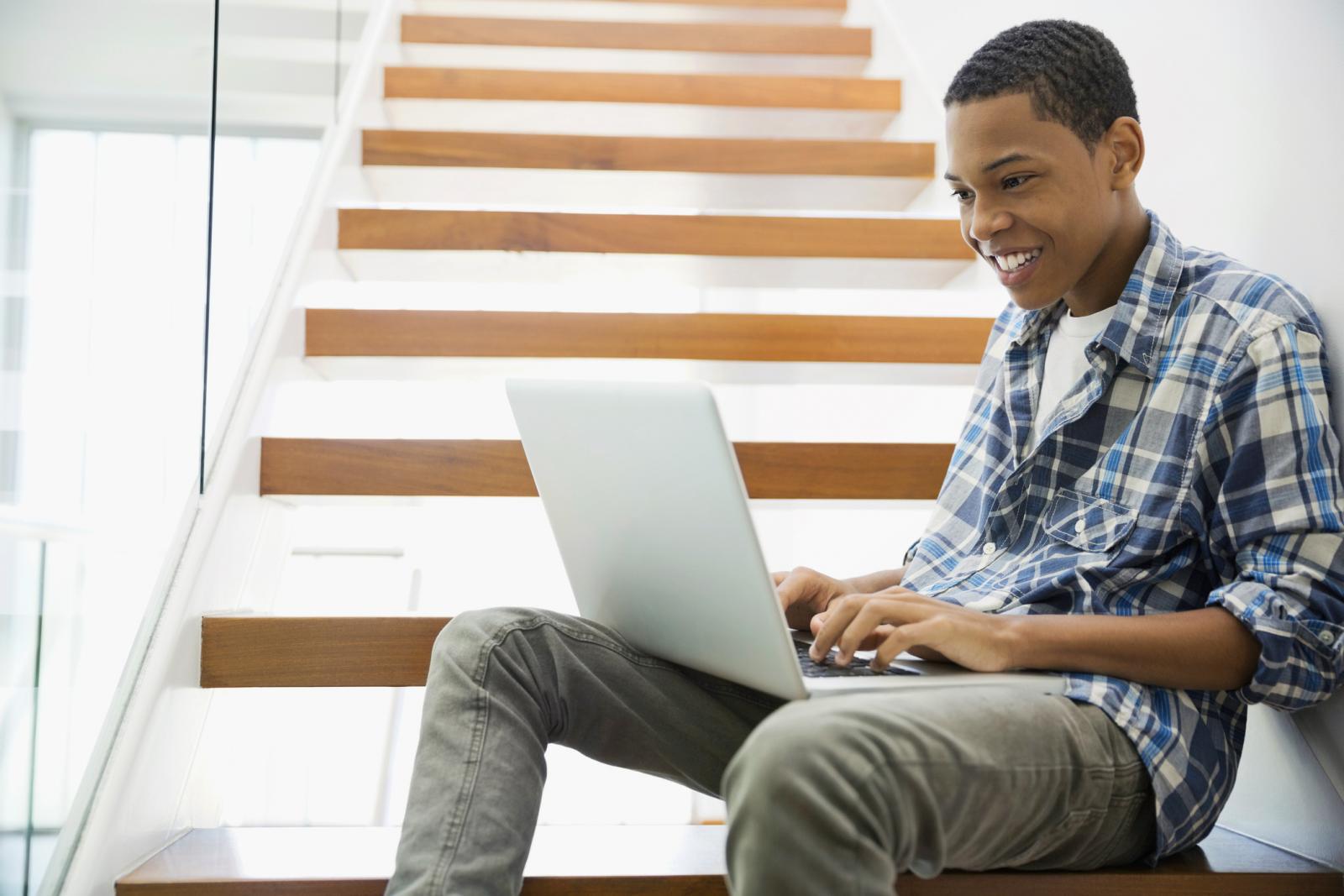 Teen using laptop on steps at home