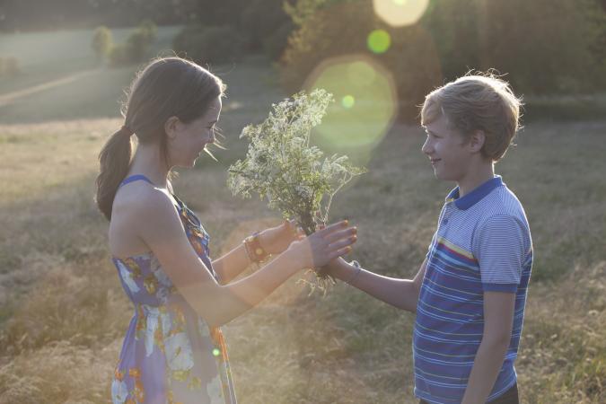 Young teen boy giving a girl flowers