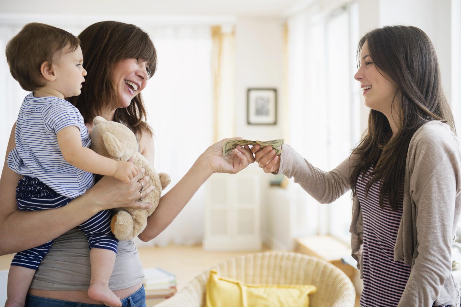 Woman paying teenage nanny for taking care of her son