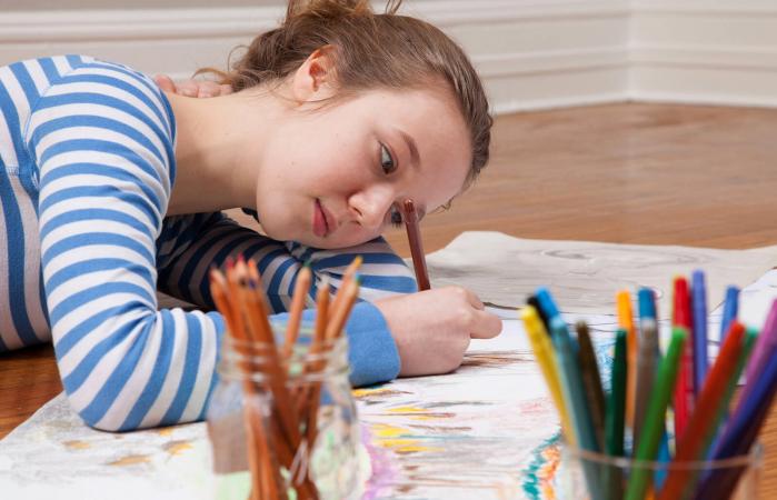 Girl lying on floor drawing picture