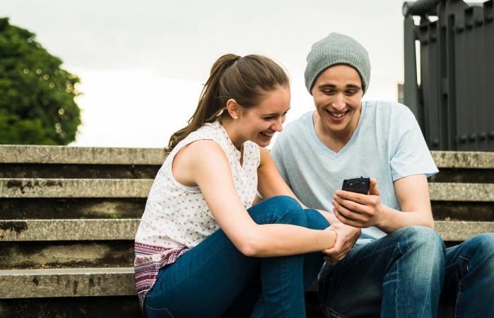 couple with smartphone sitting on stairs