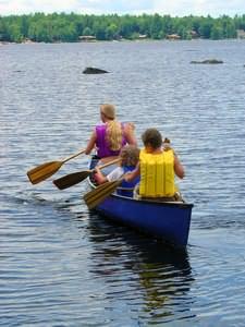 Teen camp counselor paddling a canoe with a camper