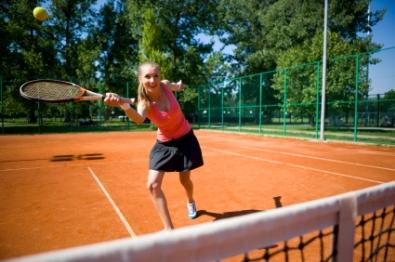 Teen girl getting exercise playing tennis