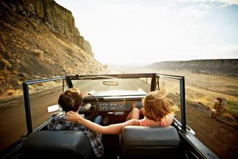 couple driving convertible at sunset