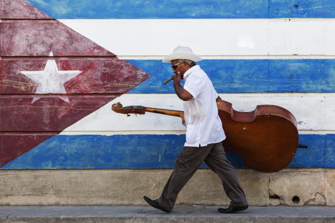 musician in front of Cuban flag mural