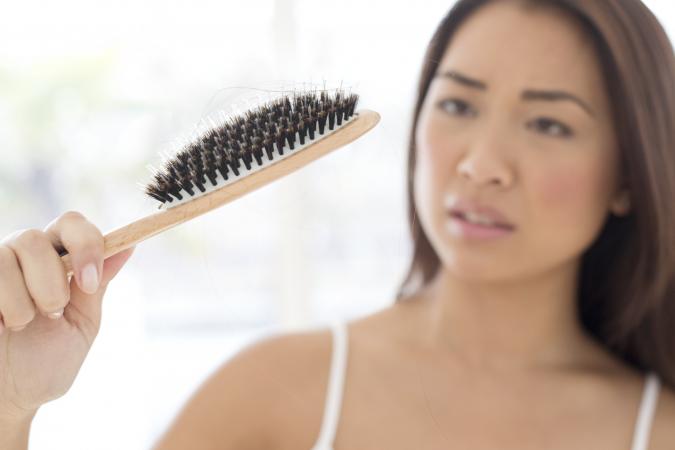 Woman holding hairbrush with worried expression