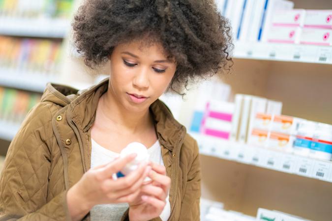 woman reading label on vitamin bottle