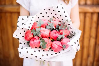 Woman holding peonies in black and white polka dot tissue