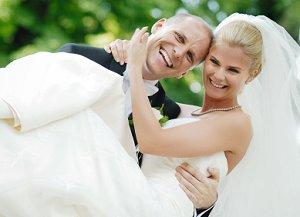 Happy groom carrying bride after the wedding