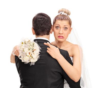 Bride hugging husband with fingers crossed