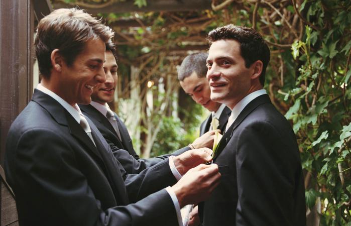 Groomsman adjusting groom's boutonniere