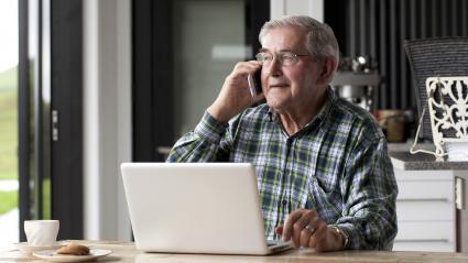 Senior male talking on smartphone while seated at table
