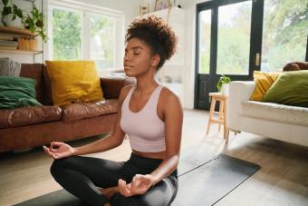 Young woman sitting on yoga mat meditating