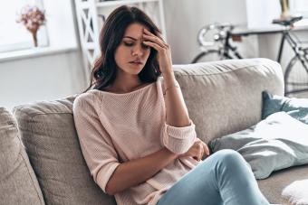 woman sitting on sofa with anxiety and gut discomfort