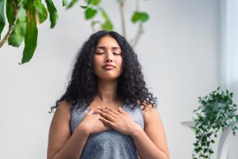 Young woman doing breathing exercise at home