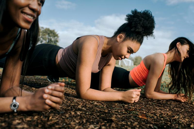 Three woman in a sunny outdoor planking