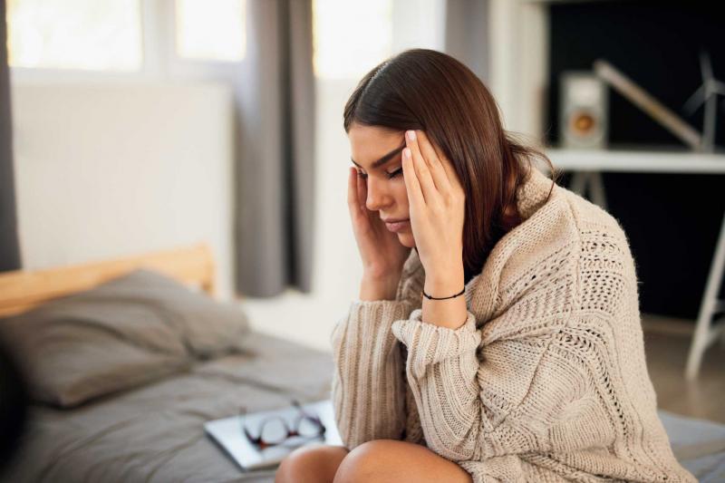 woman with stress and anxiety rubbing temples on head