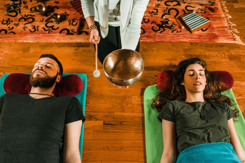 couple getting sound bath therapy by listening to singing bowl