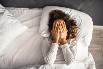 Woman with hands in her face waking up from bad dream