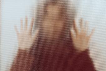 Silhouette of a woman with her hands pressed against a glass window