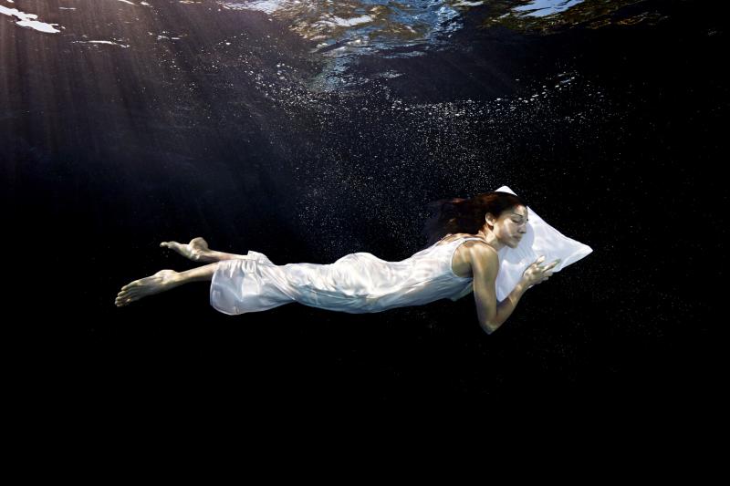 Woman with head on pillow sleeping underwater