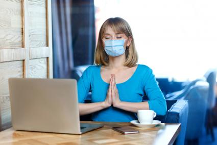 woman with surgical medical mask is sitting and working on laptop and try to relax
