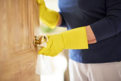 Mature woman wiping down a doorknob