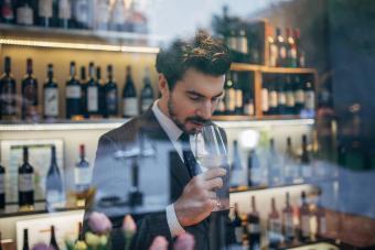 Man in a suit selling white wine before drinking it