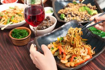 Woman eating noddles and drinking wine