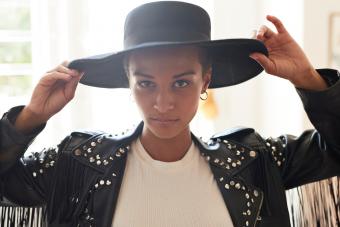 Portrait of confident young woman holding black hat