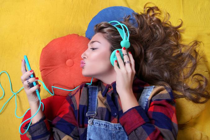 Girl wearing green headphones blowing kisses