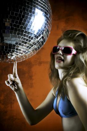 Woman in a disco outfit touching a mirror ball