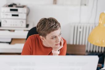 Woman at desk in office thinking 