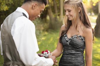 Teenage boy attaching corsage to prom date 