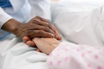 Doctor holding the hand of a sick woman in bed at the hospital 