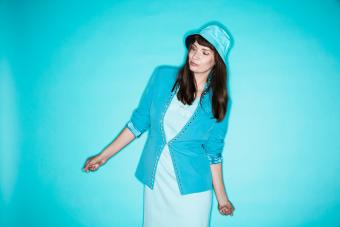 woman wearing hat while standing against blue background 