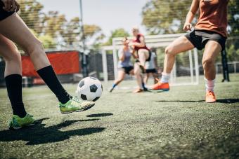 Women playing soccer in grass field