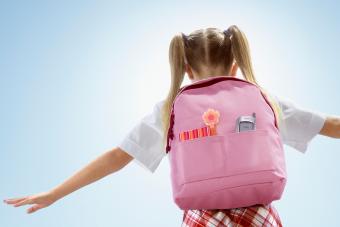 Girl (6-8) wearing pink backpack