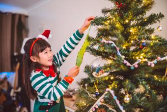 Little girl decorating Christmas tree at home