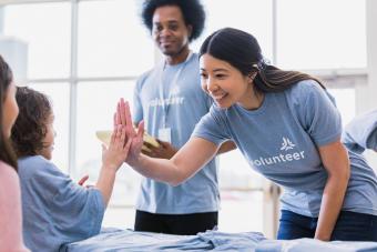 Young adult woman high fives child volunteer