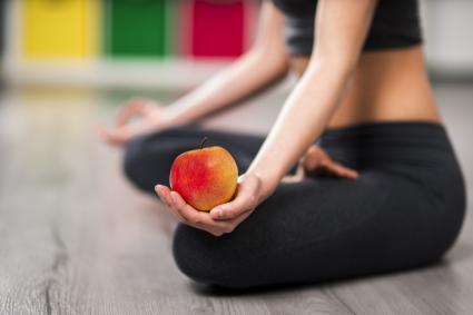 Woman on yoga mat with apple