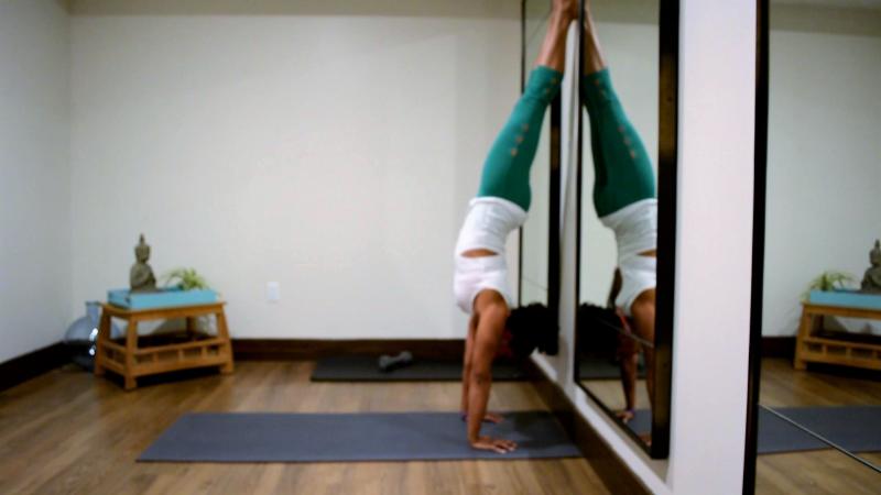 Image of woman doing yoga handstand in studio