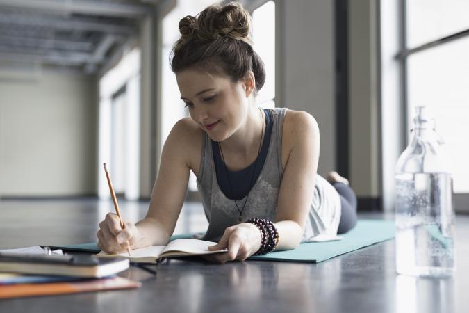 Woman on mat writing in journal