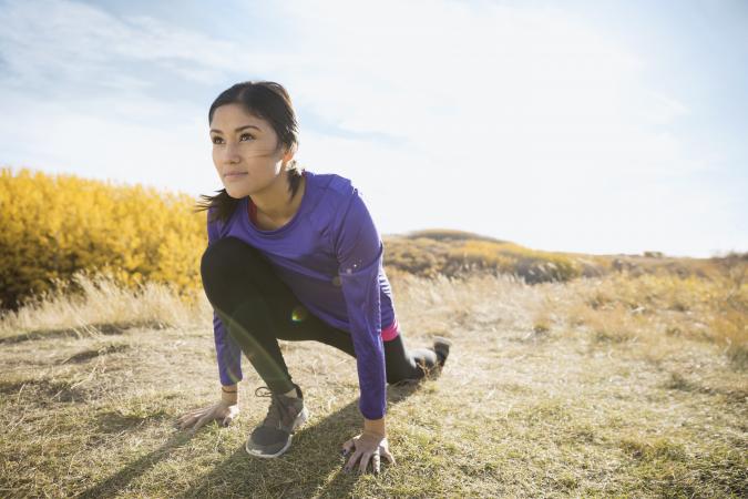 Runner stretching in sunny rural field