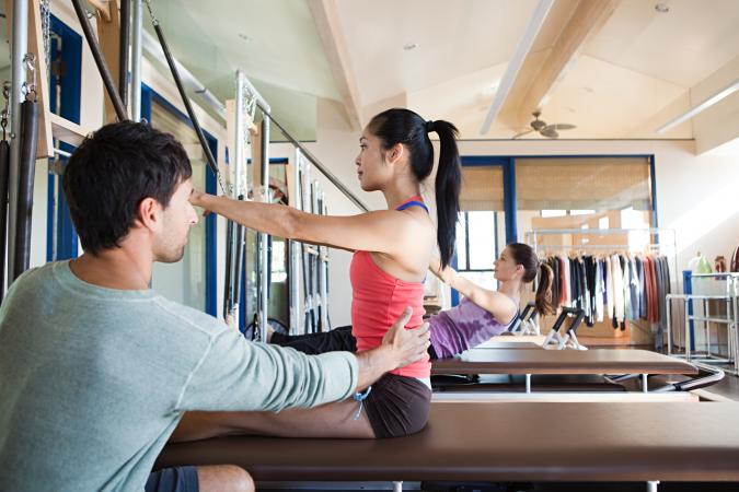 Pilates instructor assisting woman
